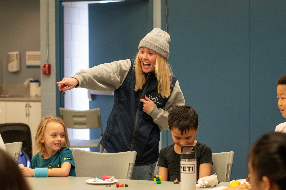 An instructor at a day camp excitedly encourages a participant.