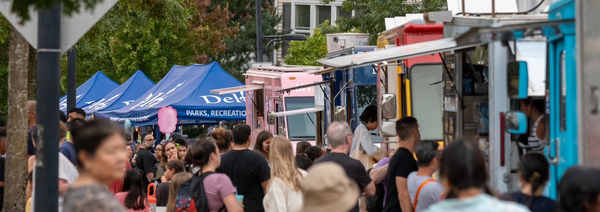 Food trucks line the street at Luminary Festival with people lined up.