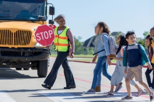 Crossing guard holding stop sign leading students through a crosswalk.